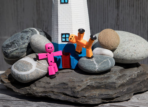 Macro, stickbots play on the rocks in front of lighthouse.