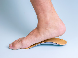 The right leg of a man with a strong flat feet trying on an orthopedic insole.