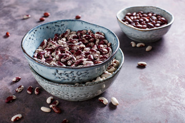 Different types of beans in bowls on a blue background.