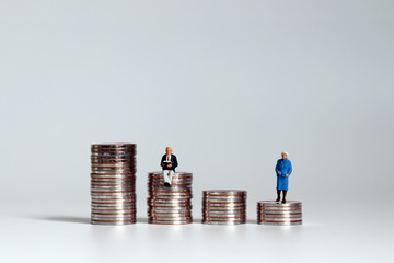The concept of saving for old age. miniature people with piles of coins