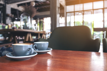 Closeup image of two blue cups of hot latte coffee on vintage wooden table in cafe