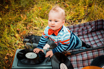 little one-year-old child sitting in an old retro suitcase in the fall outdoors