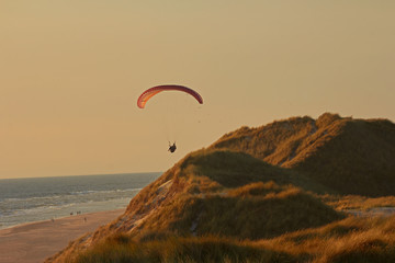 Paraglider fliegt über Dühne am Strand in Dänemark