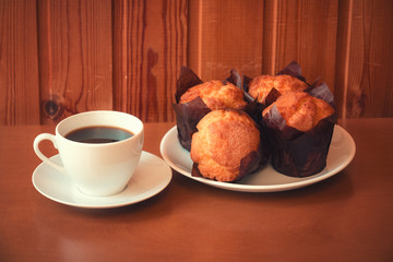 Coffee and vanilla muffins on wooden table