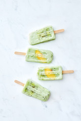 A set of delicious homemade berry ice cream lolly with a slice of mango on a gray marble table with copy space. Flat lay