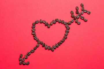 Grains of coffee in the form of heart on a red background