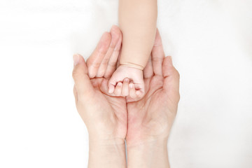 Obraz na płótnie Canvas 赤ちゃんの小さな手を包むお母さんの大きな両手のアップ。成長と健康を喜ぶ母。母性、愛情、幸せ、育児、健康のイメージ