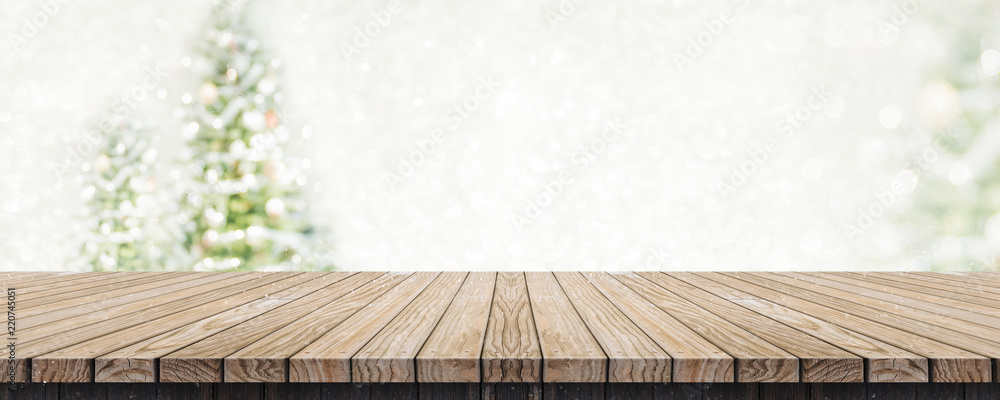 Aufkleber Empty brown wooden table top with abstract muted blur christmas tree and snow fall background with bokeh light,Holiday backdrop,Mock up banner for display or montage of product.