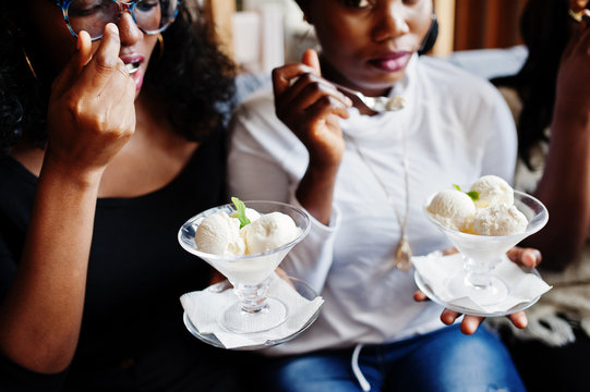 Close Up Hands Of Group African American Girls Sitting On Table At Cafe And Eating Ice Cream Dessert.