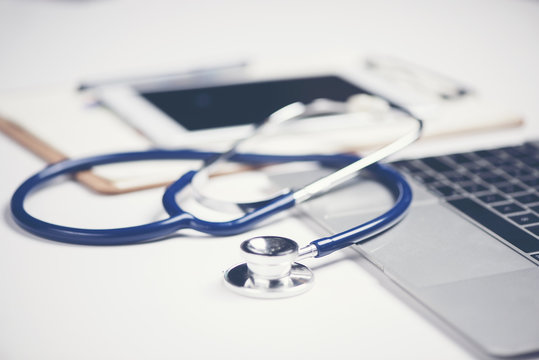 Workplace of doctor with laptop and stethoscope and notebook on white table top view shot.