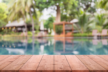 Empty wood table top and blurred swimming pool in tropical resort background. - can used for display or montage your products.