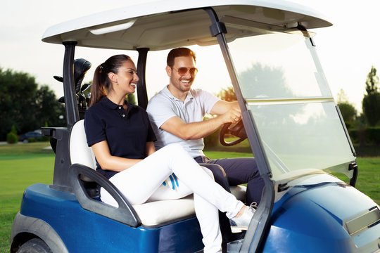 Couple smiling and driving in buggy in golf course