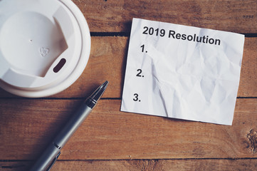 Resolution for 2019 word on paper with pen and coffee cup on wooden table. Business concept.