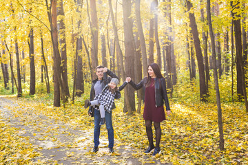 Fototapeta premium People, family and leisure concept - mixed race father and mother have fun in autumn park with their daughter