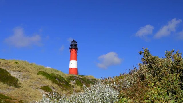 Wundersch&ouml;ner Leuchtturm H&ouml;rnum Sylt mit D&uuml;nen Landschaft  und blauen Himmel
