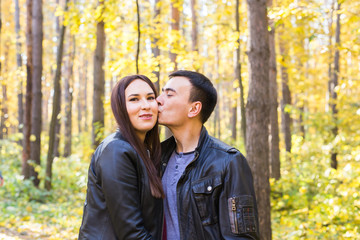 love, relationship, family and people concept - man kissing his wife in autumn park