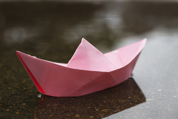 pink paper boat on wet asphalt, mood concept