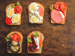 sandwiches with various food ingredients on a wooden background.