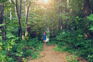 Fototapeta premium Nature, people and lifestyle concept - Beautiful young woman in dress runing in the summer forest
