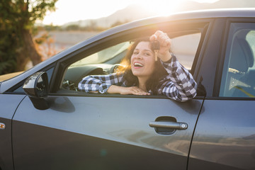New car, purchase and driver concept - Young woman showing key in a car