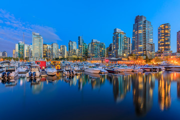 Fototapeta na wymiar Sunset at Coal Harbour in Vancouver British Columbia with downtown buildings boats and reflections in the water