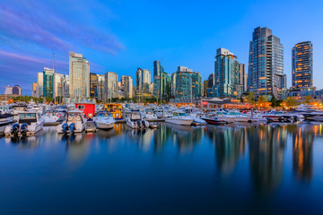 Naklejka premium Zachód słońca w Coal Harbour w Vancouver w Kolumbii Brytyjskiej z łodziami śródmieście budynków i odbicia w wodzie
