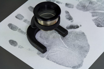 The investigation of the crime. A fingerprint on a paper with a magnifying glass