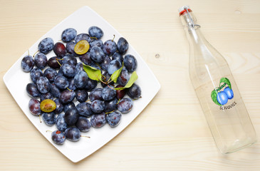 Fresh plums with leaves on a wooden table background. Flat lay composition.