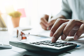 Businessman with calculator counting making notes at office hand is writes in a notebook