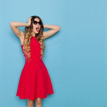 Bautiful Woman In Red Dress And Sunglasses Is Holding Head In Hands And Shouting