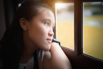 Asian girl near window thinking about something