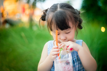 Little girl drinking water through a straw