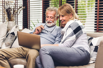 Senior couple relaxing and using laptop computer together sitting on sofa in living room at home.Retirement couple concept