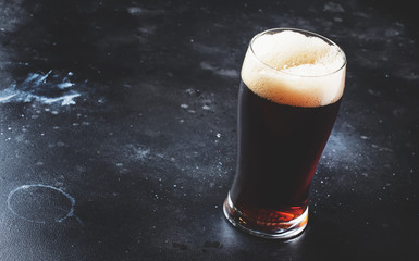 Dark english beer, ale or stout is poured into glass, dark bar counter, space for text, selective...