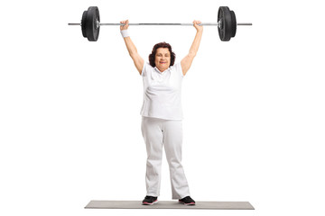 Mature woman standing on an exercise mat and lifting a barbell with one hand
