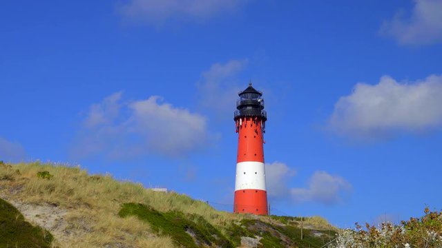 Wundersch&ouml;ner Leuchtturm H&ouml;rnum Sylt mit D&uuml;nen Landschaft  und blauen Himmel
