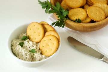 Snack from crackers and curd fish paste with herbs on a light background.