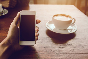 Close up of man hands holding touching mobile phone with blank copy space for your text message in cafe with light Sunset,Vintage tone.Selective focus