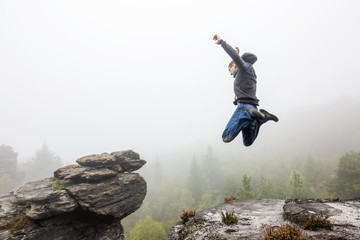 Mann macht Freudensprünge auf den Berggipfel