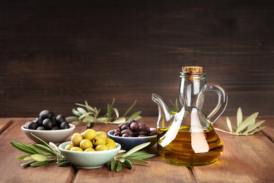 Various olives and bottle of olive oil on a dark background with copy space