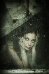 sensual young woman portrait behind old dirty window