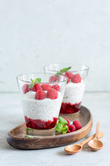 Chia pudding with raspberries in a glass on wooden serving board. Copy space for text. Concept of healthy lifestyle, healthy eating, vegan and vegetarian diet