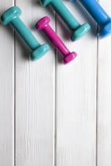 Colorful dumbbells on a wooden background