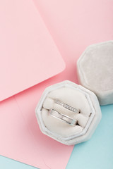 Two silver wedding rings with diamonds on pink background