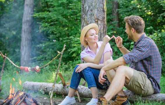 Couple tourists hold gesture while sit log bonfire. Man and girl play hand game. Couple play hand game. Hand gesture game decide who win. Play while wait roasting food. Reconciliation gesture