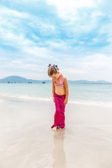 Little beautiful girl dressed in swimsuit as a mermaid stands on the seashore