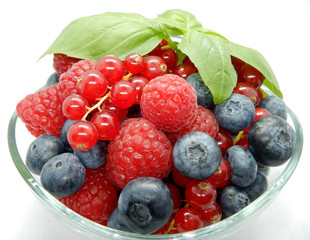 Berries in bowl, assorted mix of fruits, raspberry, red currant, blueberry against a white background