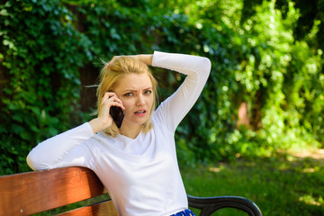 Woman heard bad news. Bad news. Girl blonde tense face talk smartphone green nature background....