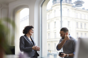 Smiling business colleagues communicating at office