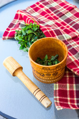 A wooden village mortar for herbs and spices with mint inside. Peppermint for cooking and cosmetology concept. Rural style